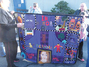 A blanket honoring the memory of Deanna Cremin was displayed and carried along as community members “Walked Deanna Home” on Saturday. ~Photo by Donald Norton