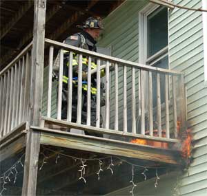 Firefighter Tom Ross works to extinguish flames spreading in a rear wall of 68-70 Holland Street on April 16. ~Photo by Somerville Fire Department. 