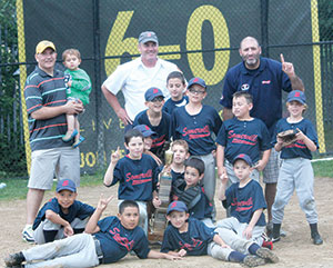 1st row, lying down left to right: Alvin Benavides, Brady Sullivan; 2nd row, kneeling left to right: Robert Benavides, Matthew Barton, William Capuano, Harry Hall, Aidan O’Donovan, Austin Pereira; 3rd row, standing left to right: Max Hall, Nate Bogosian, Travis Freitas, Dillion Marujo, Owen Carr; 4th row, standing left to right: Assistant Coach Chris Hall, holding his son Jasper, Assistant Coach Brian O’Donovan, and Head Coach Sean Sullivan.